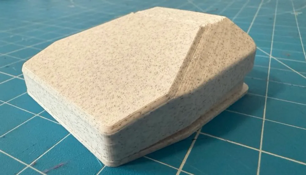 A white and grey speckled foot pedal sitting on a blue mat.